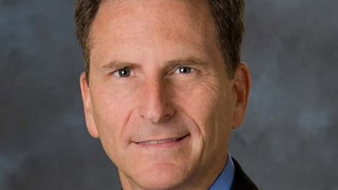 a man wearing a suit and tie smiling and looking at the camera